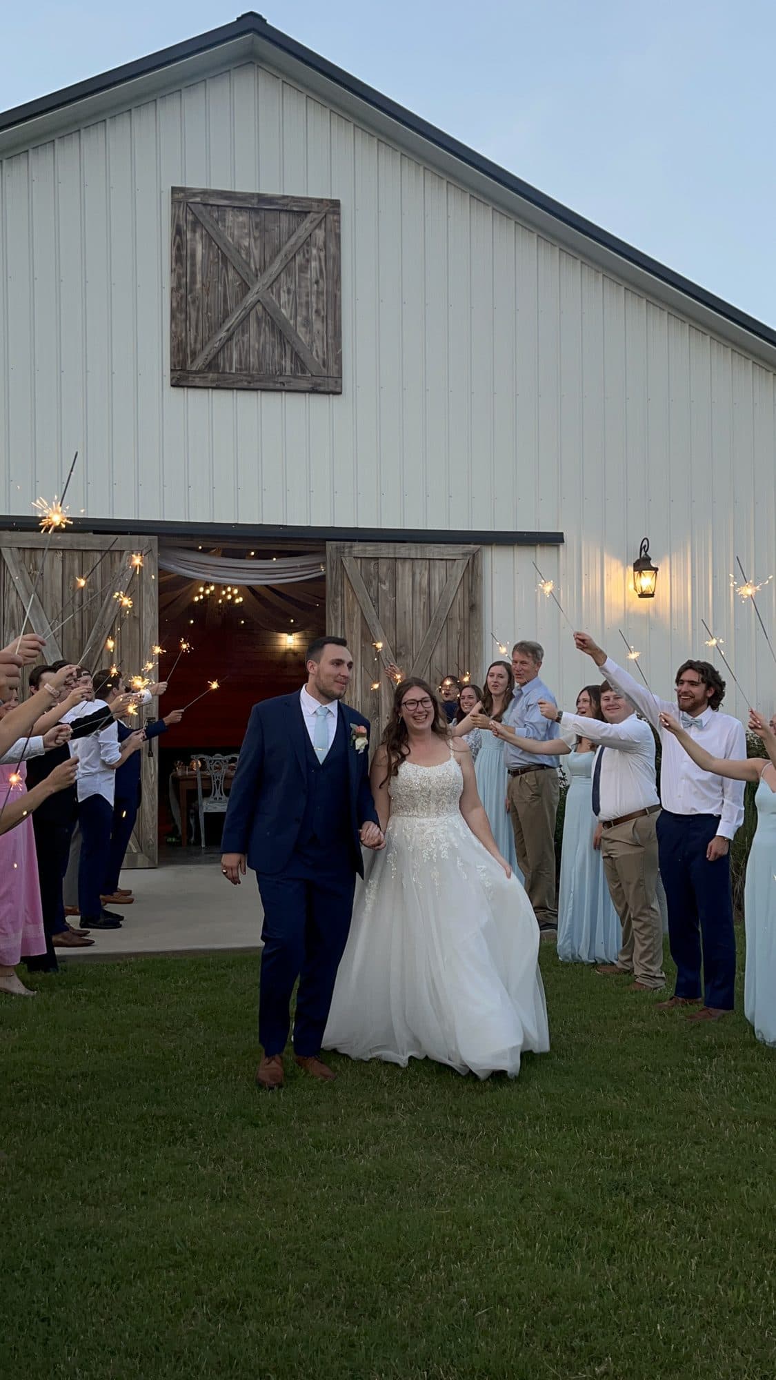 The newlyweds walking hand in hand out of the barn through a tunnel of guests’ sparklers
